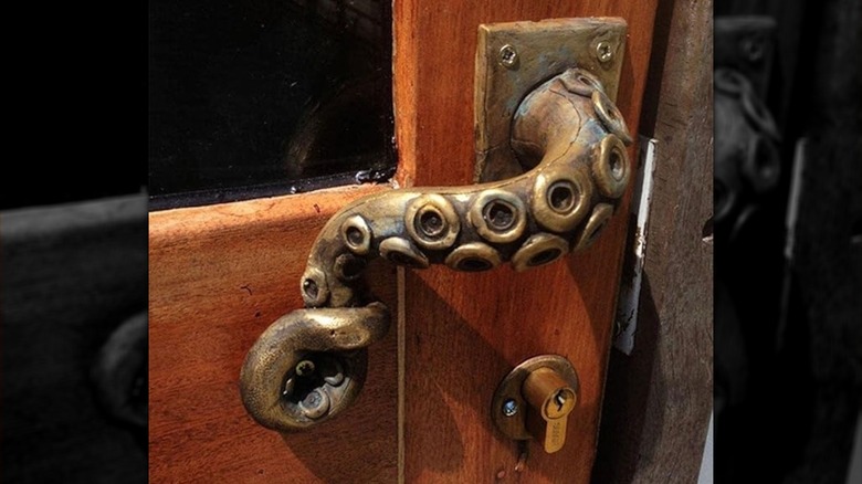 brass octopus tentacle door handle installed on wood door with glass window