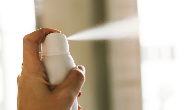 close up of hand spraying an aerosal disinfectant