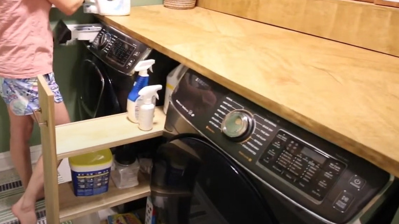 Storage sliding cart between laundry machines with detergent on it