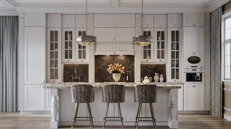 traditional kitchen with glass cabinets surrounding an ornate range hood and an island in front with three barstools