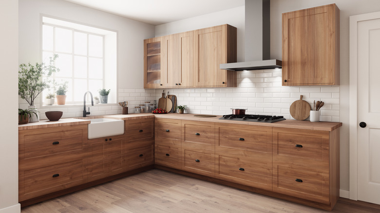 modern kitchen with natural wood cabinets, wood countertops, white apron sink, and a white tile backsplash