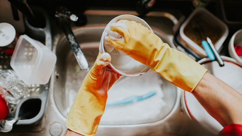 person wearing rubber gloves handwashing dishes