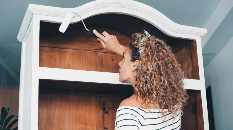 woman painting bookshelf