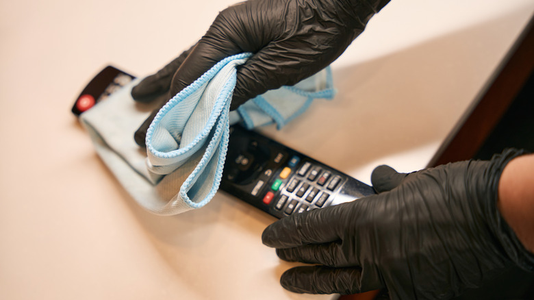 Wearing black nitrile gloves while cleaning a remote control