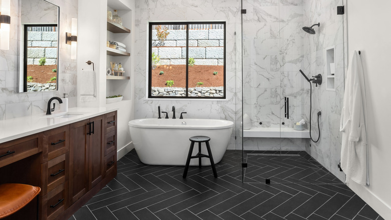 bathroom with marble walls and black herringbone flooring