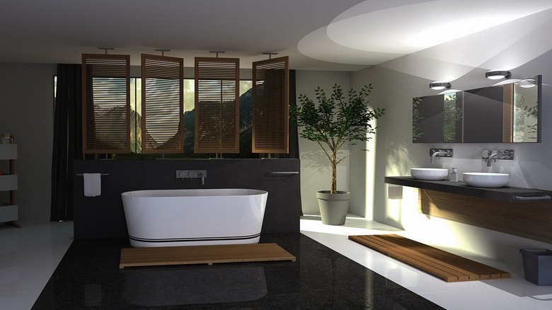 modern bathroom with white tile floor and black tile flooring surrounding freestanding bathtub