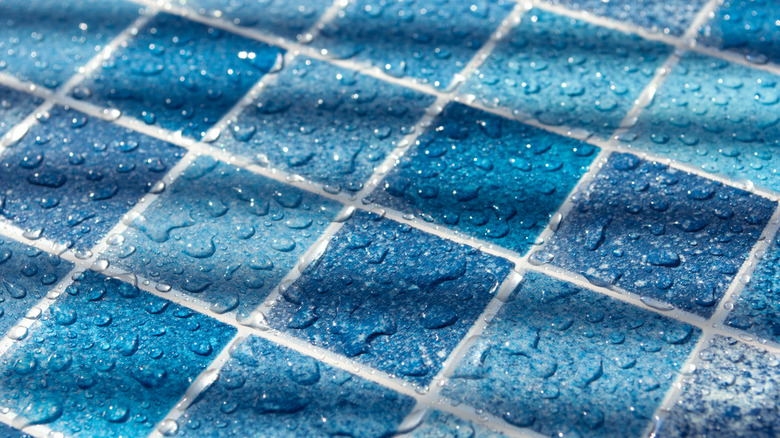 closeup of shimmering blue square tiles of various shades with droplets of water on them