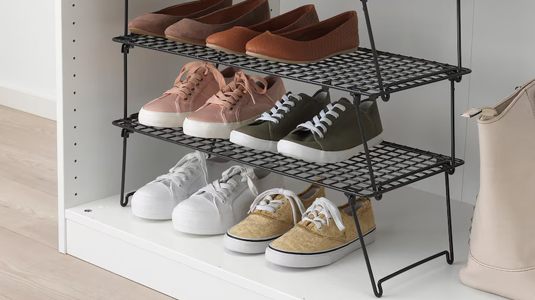 white wardrobe cabinet with three IKEA GREJIG show racks stacked on top of each other, full of shoes, on the bottom shelf