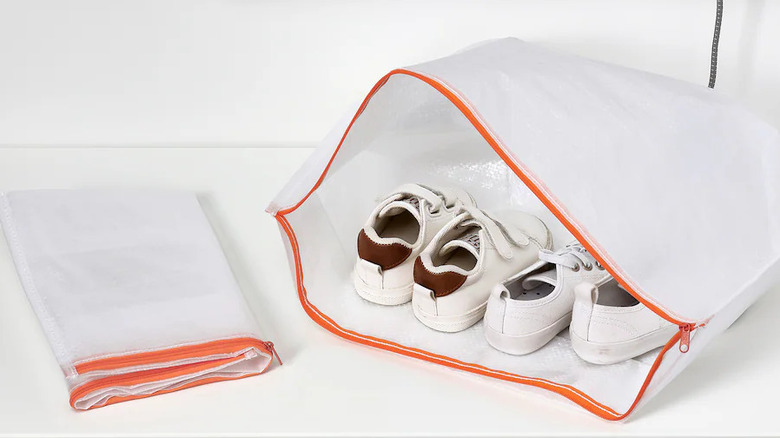 one folded IKEA PÄRKLA shoe bag and one open PÄRKLA back with two pairs of white sneakers sitting on a white shelf