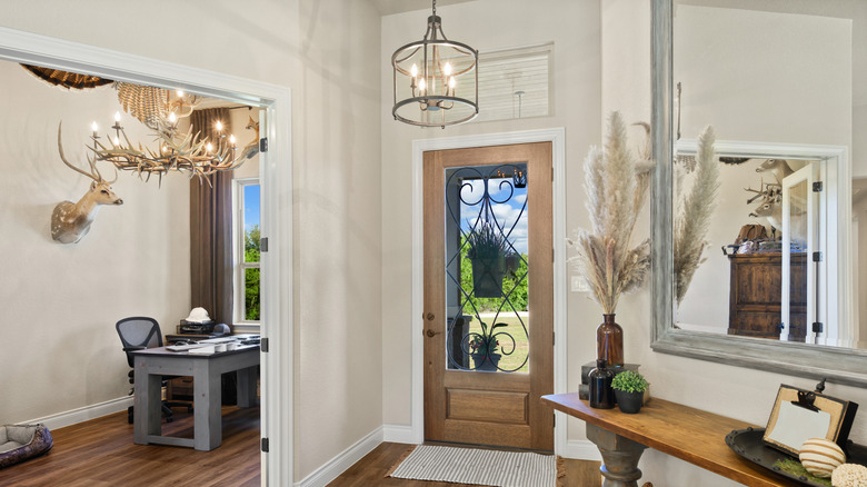 entryway with hanging lighting, mirror,and table with decor