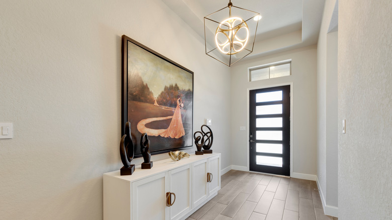 indoor entryway with large painting, abstract sculptures and lighting