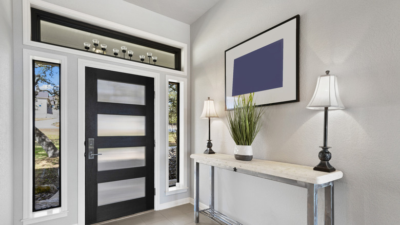 entryway with statement lighting, framed art, table with lighting and plants