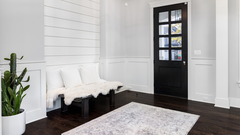 cozy entryway bench with pillows, blanket, rug and plant