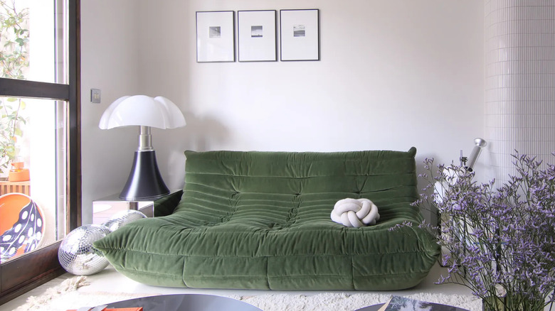 living room with a replica of a green fabric tufted Togo sofa