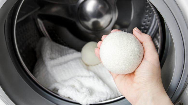 Hand holding a dryer ball and placing it in a dryer