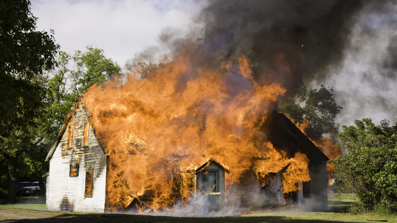 white wooden house on fire smoke billowing toward the sky