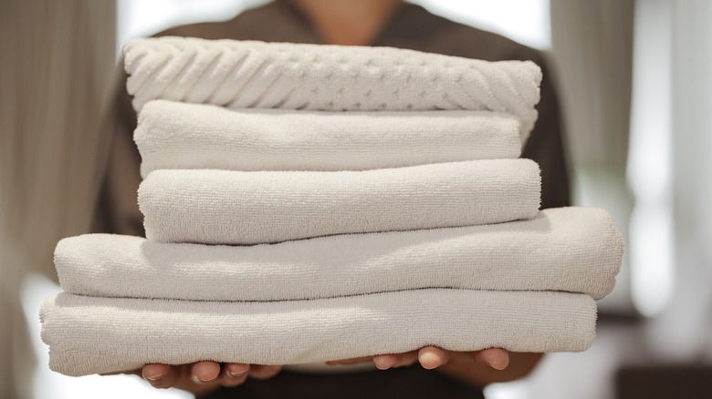 woman holding white bath towels and bath sheets