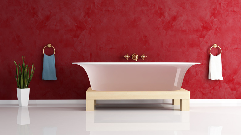 Freestanding bathtub against a red-painted wall