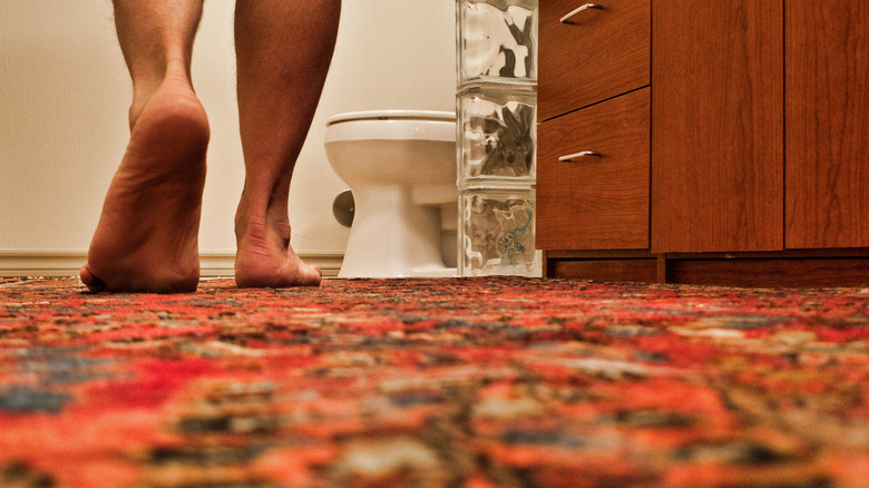 Person walking on multi-colored carpet in bathroom