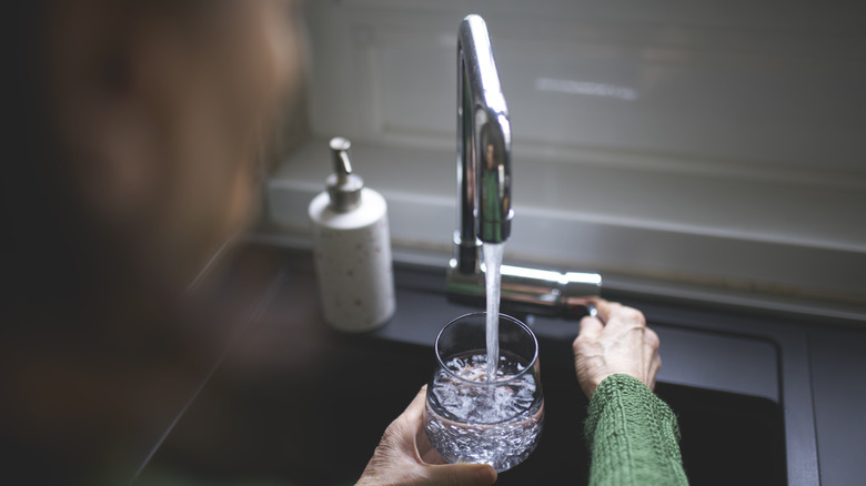 Woman adding tap water to glass