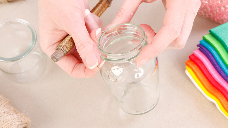 hands holding a mason jar around which they are adding wiring for an arts and craft project