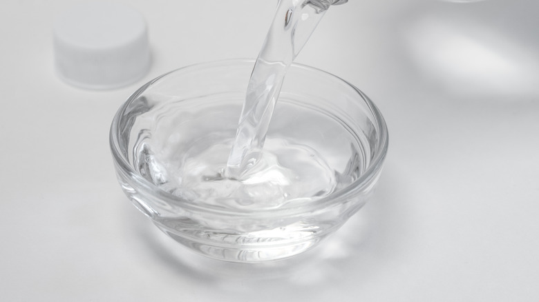 Distilled vinegar is being poured into a small glass bowl.