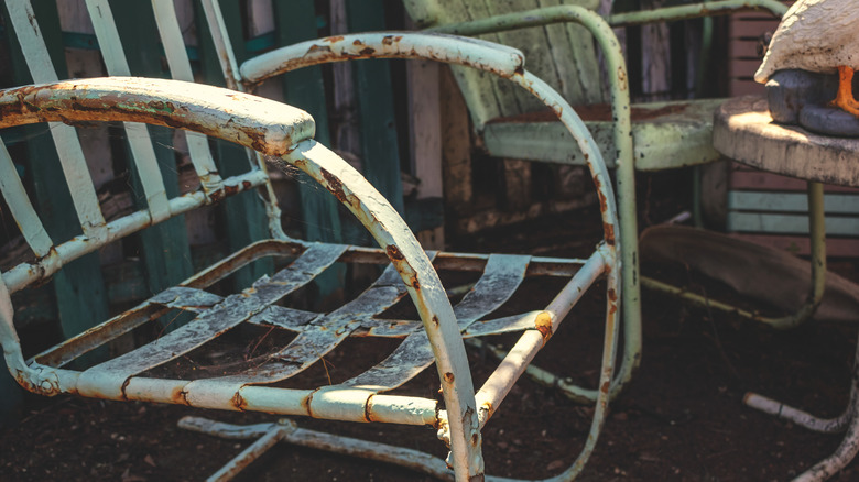 A set of outdoor patio furniture is shown to be rusted and covered with spider webs.