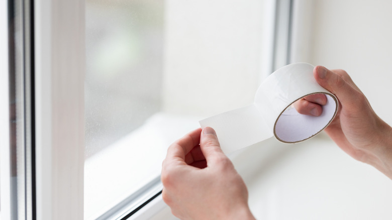 Man holding tape by window