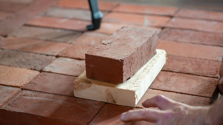 bricks laid out for a hearth with a mans hand