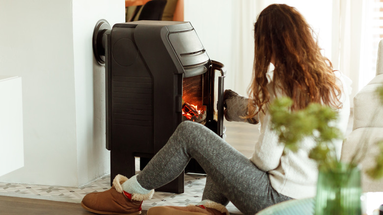 Woman tending the fire in a modern wood stove