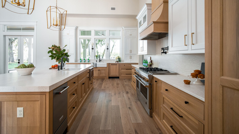 luxury kitchen with brown cabinets, marble counters, and elegant light fixtures