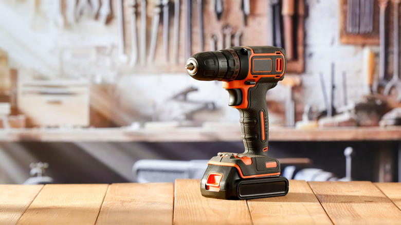 Cordless drill situated in front of many hand tools