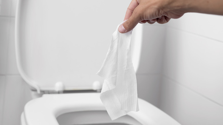 holding wet wipe over toilet