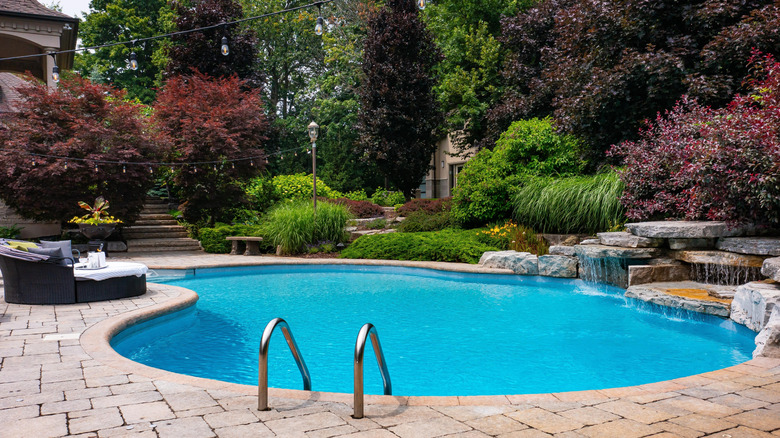 luxury backyard with swimming pool, water fall, and outdoor patio