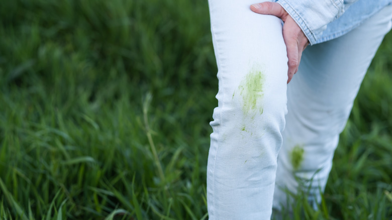 Person examining grass stains on pants