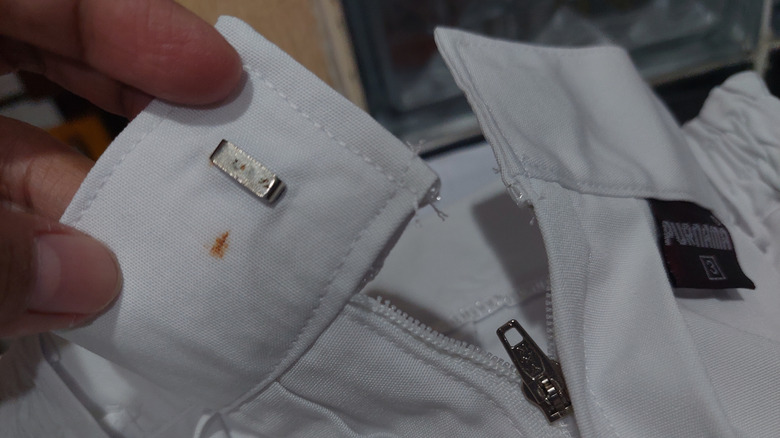 Close-up of a rust stain near a zipper on white jacket