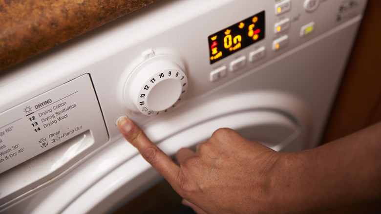 person pressing buttons washing machine