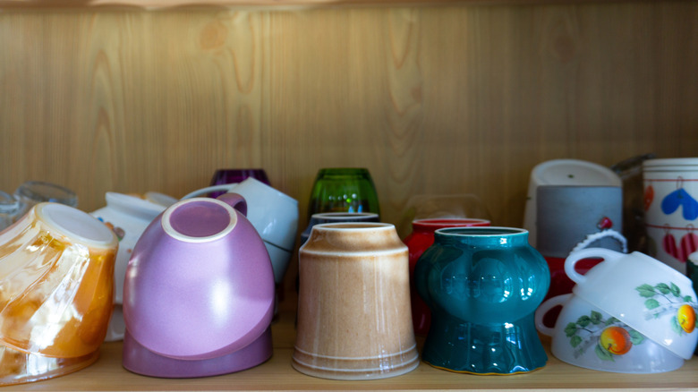 stacked colorful mugs in a cabinet