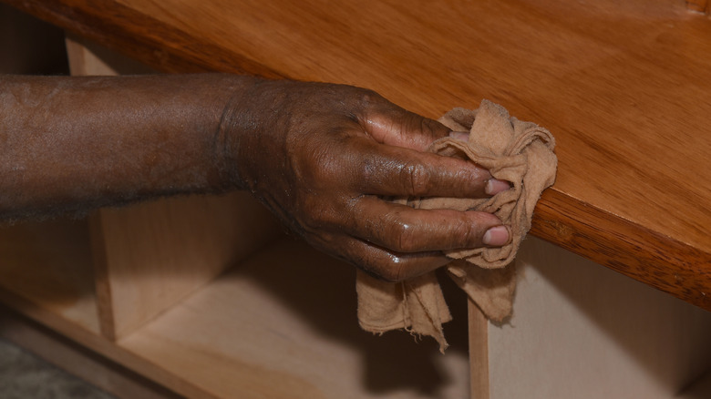 hand wiping down staining on a kitchen wooden counter with a rag