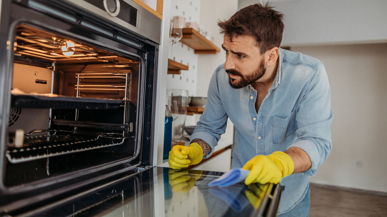 Man cleaning and inspecting inside of an oven