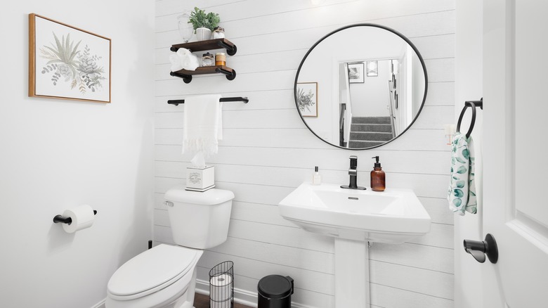 A small white powder room with a shiplapped accent wall