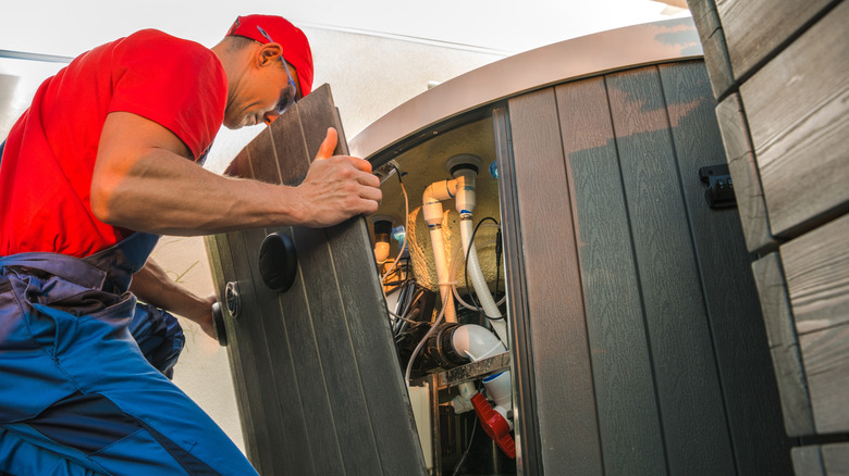 A technician opening a hot tub to inspect its pump