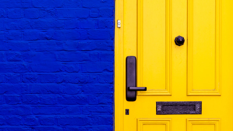 Close-up of a bright blue brick home with a yellow door.