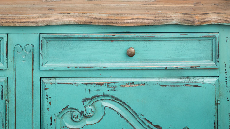 A vintage dresser has a natural wood top, while the front is distressed and painted aqua.