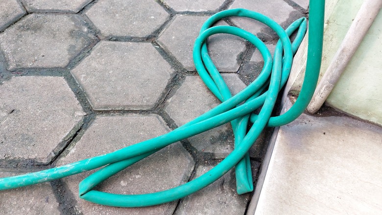 A worn old garden hose on a patio