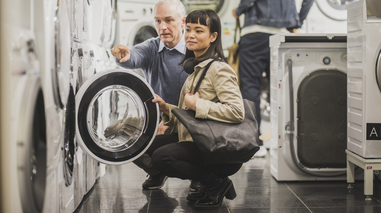 Old man and young woman shopping for laundry machines