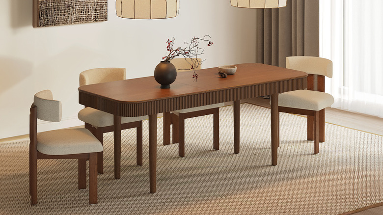 Dining room with off-white walls, cream rug, a rich stained wood reeded dining table, and four mid-century wood chairs with white upholstery