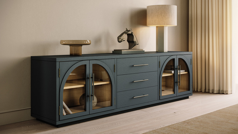 Black wood media console with two sets of glass arched cabinet doors on the sides and a bank of three drawers in the middle