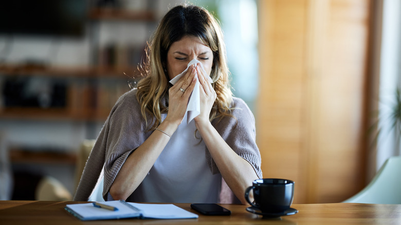 Woman sneezing at a desk