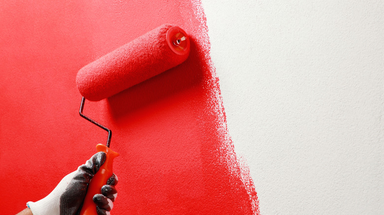 red paint being applied to wall with roller